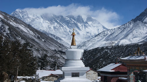 Snow covered buildings and mountains against sky