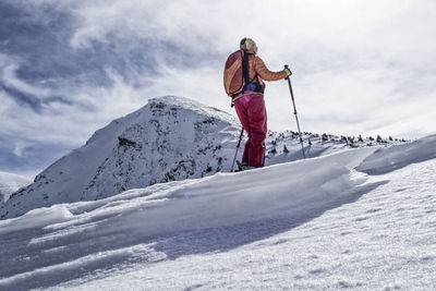 Woman skiing on snowcapped mountain against sky