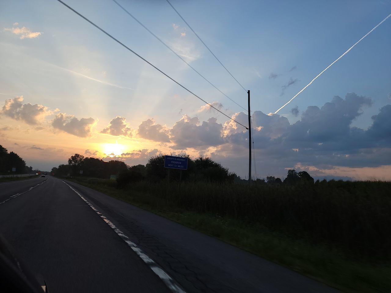 sky, road, cloud, transportation, sunset, electricity, nature, cable, landscape, technology, environment, horizon, electricity pylon, power line, no people, scenics - nature, beauty in nature, dusk, plant, evening, highway, power supply, land, outdoors, tree, rural scene, street, tranquility, sun, power generation, mode of transportation, vanishing point, travel, the way forward, city, diminishing perspective, infrastructure, tranquil scene, sunlight, dramatic sky, sign, field, car, silhouette