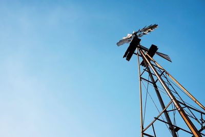 Low angle view of american-style windmill against clear blue sky