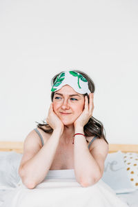 Portrait of a smiling young woman sitting on bed