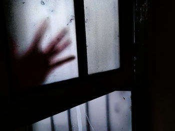 Close-up of woman hand by glass window in building