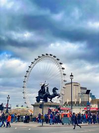 People in amusement park against sky