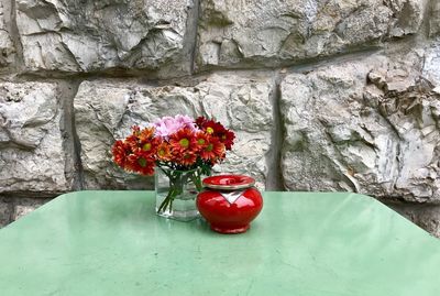 Red flowers in vase against wall