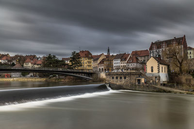 River amidst buildings in city against sky