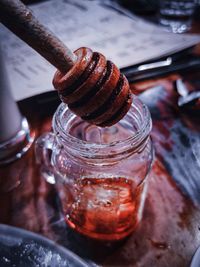 Close-up of honey dipper over jar at table