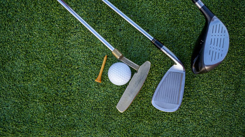 Golf clubs and golf balls on a green lawn in a beautiful golf course with morning sunshine. 