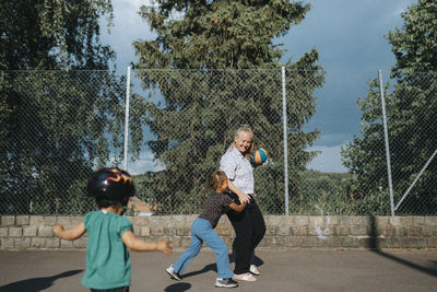 Mother and daughters playing basketball outdoors