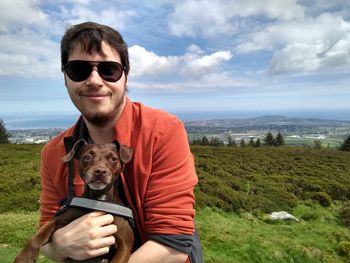 Portrait of man with dog against sky