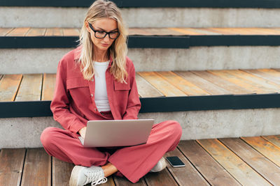 A woman with a laptop is sitting on the terrace.