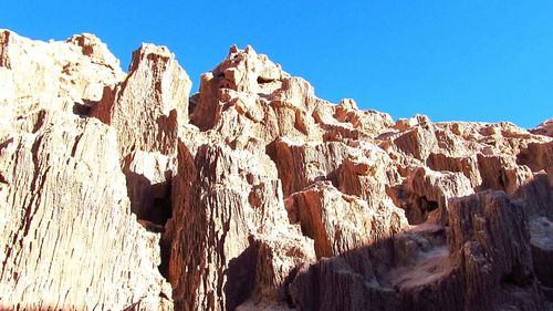 Low angle view of rock formations against clear blue sky