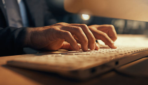 Cropped hand of man using laptop on table