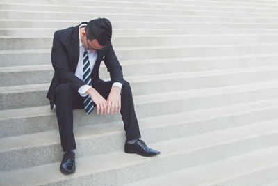 Full length of businessman sitting on steps