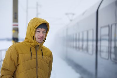 Young man travel by train during frosty day. passenger on platform railroad station in winter day.