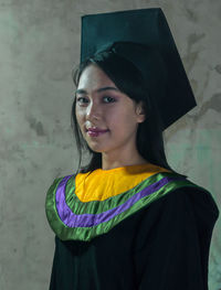 Portrait of a smiling young woman standing against wall