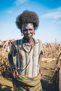 Portrait of man standing on field against sky