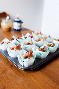 The plate of tasty cupcakes decorated with strawberry, fig and cream