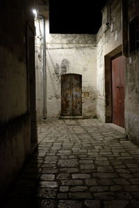 Empty alley amidst buildings in city at night