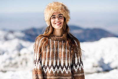 Portrait of smiling young woman standing outdoors during winter