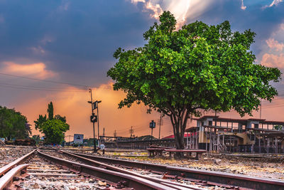 Railroad tracks in city against sky during sunset