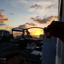 Eyeglasses and scenic view of city during sunset