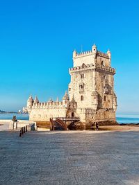 Buildings by sea against clear blue sky