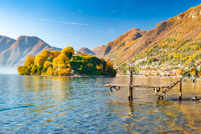 Comacina island, photographed in autumn, with trees, boats and piers around.