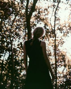Rear view of woman standing alone in forest