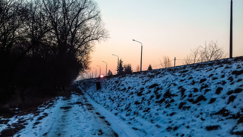 Snow covered landscape against sky during sunset