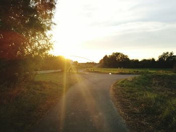 Road amidst trees against sky during sunset