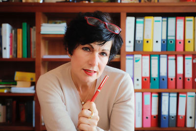 Portrait of woman sitting against book at office