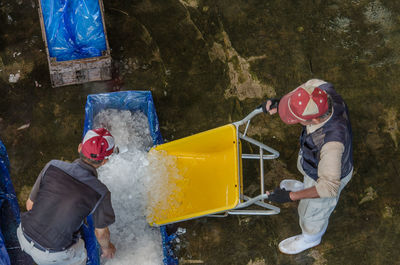 High angle view of people packing ice in plastic bag