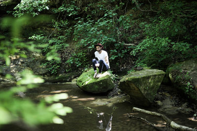 Man standing by waterfall in forest