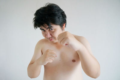 Portrait of shirtless man standing against white background