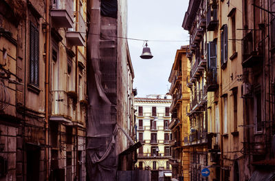 Low angle view of lighting equipment hanging amidst residential buildings against sky