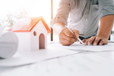 Midsection of man holding paper while sitting on table