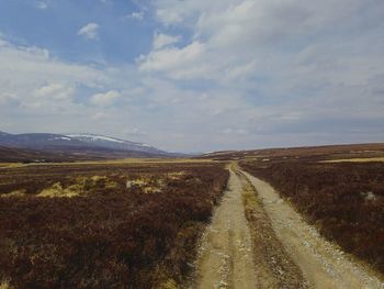 Road amidst field against sky