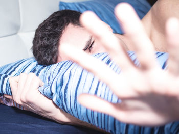 Sunlight falling on man gesturing while lying on bed