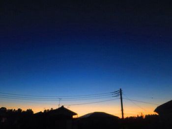 Silhouette electricity pylon against clear sky at sunset