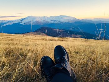 Low section of person standing on mountain against sky