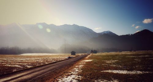 Road by mountains against sky during winter