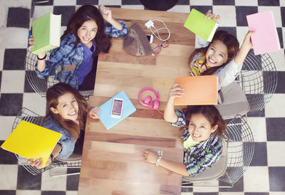 High angle portrait of cheerful female friends sitting at table in cafe