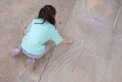 Girl draws with colorful crayons on pavement. children's drawings with chalk on wall. creative kid. 