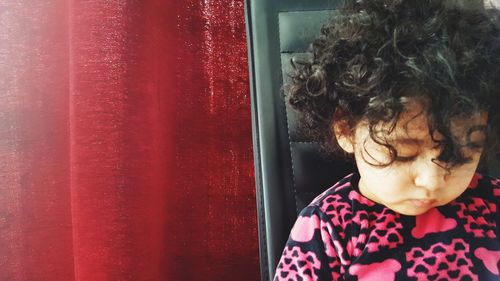 Cute girl sitting on chair against curtain