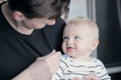 Close-up of father feeding food to baby boy at home