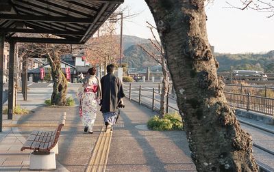 Rear view of people walking on footpath in city