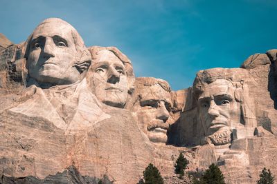 Low angle view of statues against blue sky