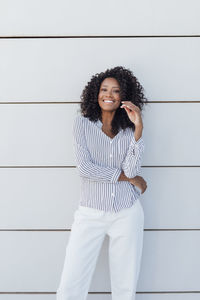 Happy young woman standing in front of wall