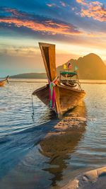 Close-up of longtail boat moored on lake during sunset