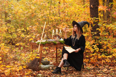 Young woman sitting on leaves during autumn